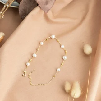 Bracelet de cheville tendance nommé PERLA posé sur une nappe beige